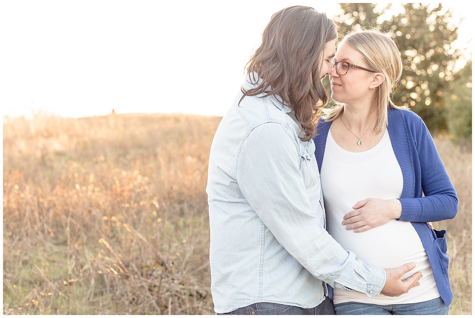 Pregnant Mom in white shirt and blue sweater, out in nature at sunset
