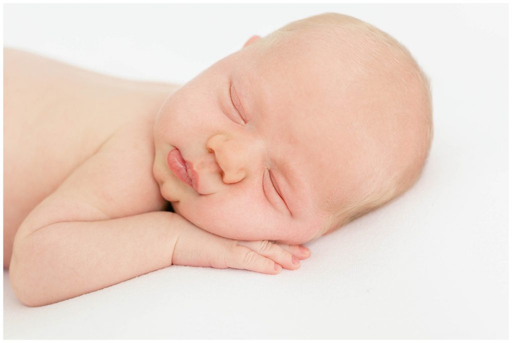 Beautiful, artistic Newborn portrait sleeping soundly on a white blanket