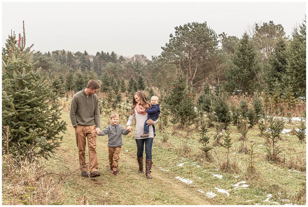 Family of four walking through a Christmas Tree Farm