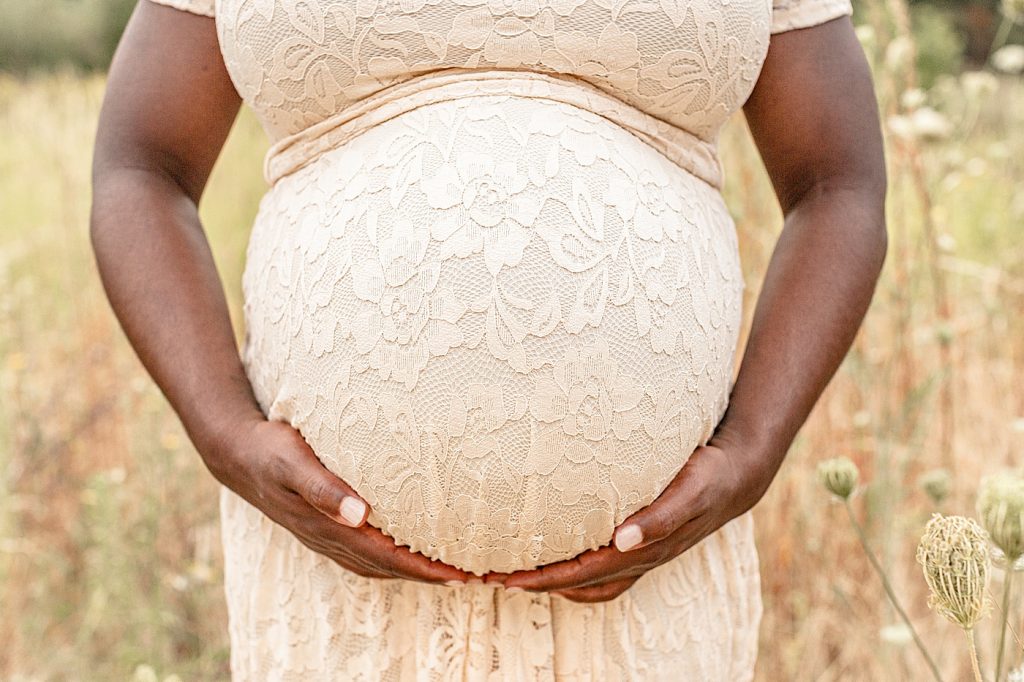 Photo of black skinned pregnant woman holding her belly