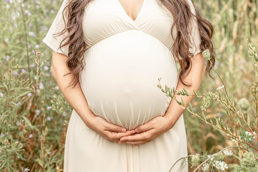 Close up photo of pregnant belly and woman holding belly underneath
