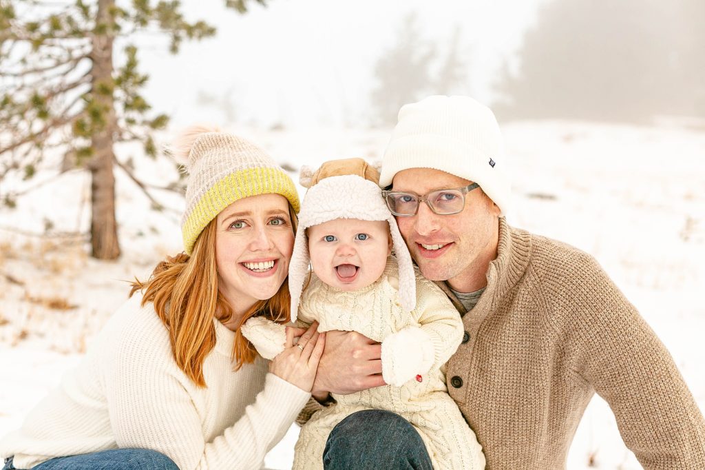 Light skinned family of 3 out in snowy scene wearing light colored sweaters and hats - documenting baby's first year