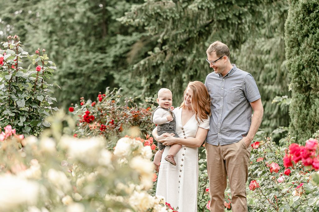 Light-skinned parents with one year old baby in the rose gardens for photo session documenting baby's first year