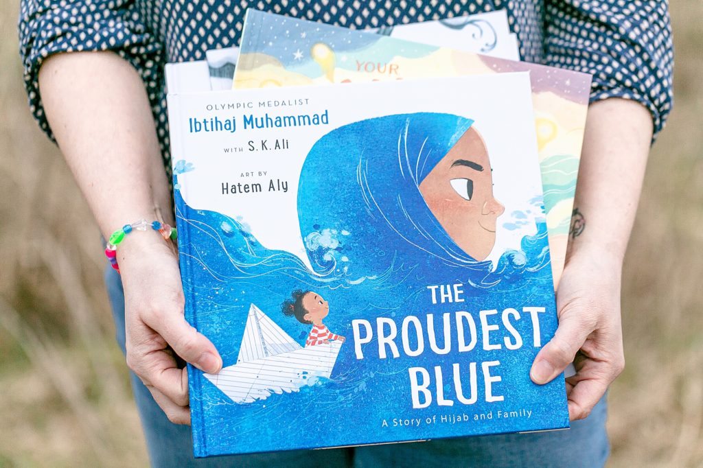 A woman holding the book, "The Proudest Blue"