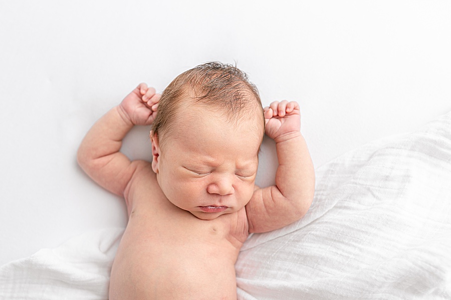 Newborn baby lying on white blankets with arms up - Portland Oregon Newborn Photography Studio