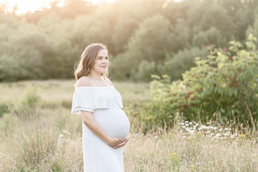 light-skinned woman in a white dress outdoors for maternity photo session
