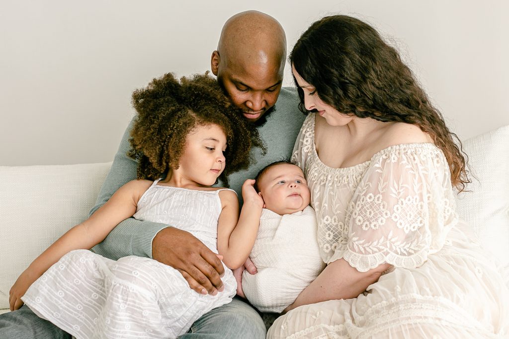 family of four looking at new baby during family studio newborn photography session