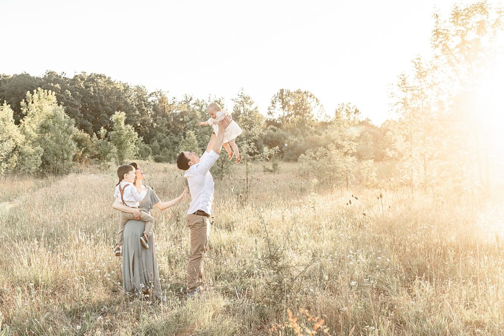 Dad throwing little girl in air during summer outdoor family photography session.