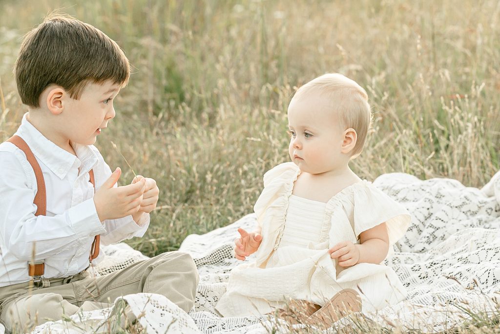 big brother and little sister talking to each other during their outdoor family photo session