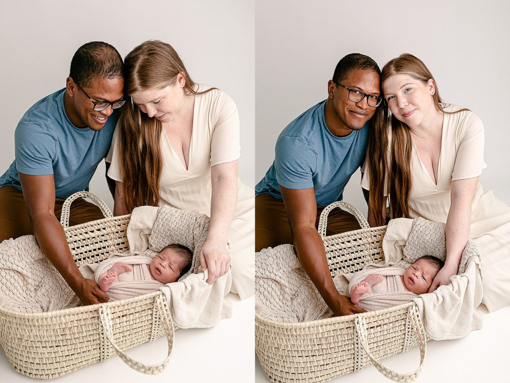 Mixed race couple sitting next to baby in Moses basket during newborn photography session