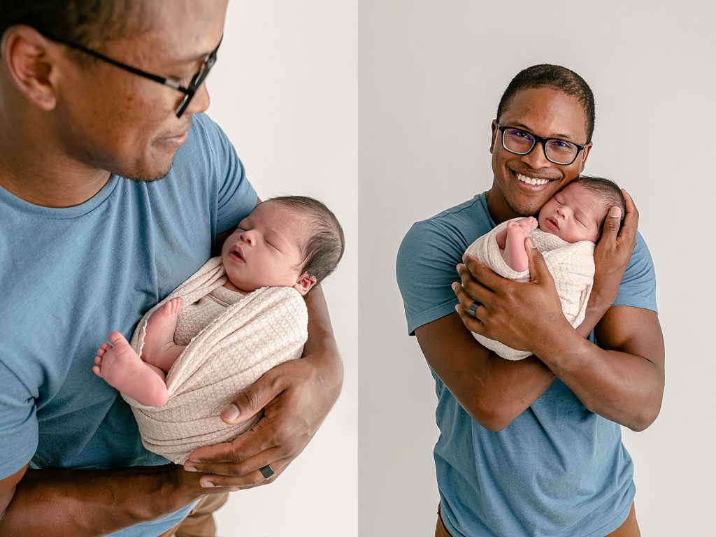 dad in blue shirt holding baby in cream swaddle during newborn photography session