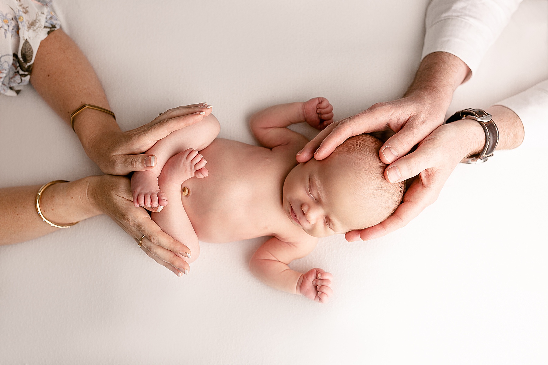light-skinned parent hands on light-skinned newborn baby on white backdrop - portland oregon newborn portrait studio