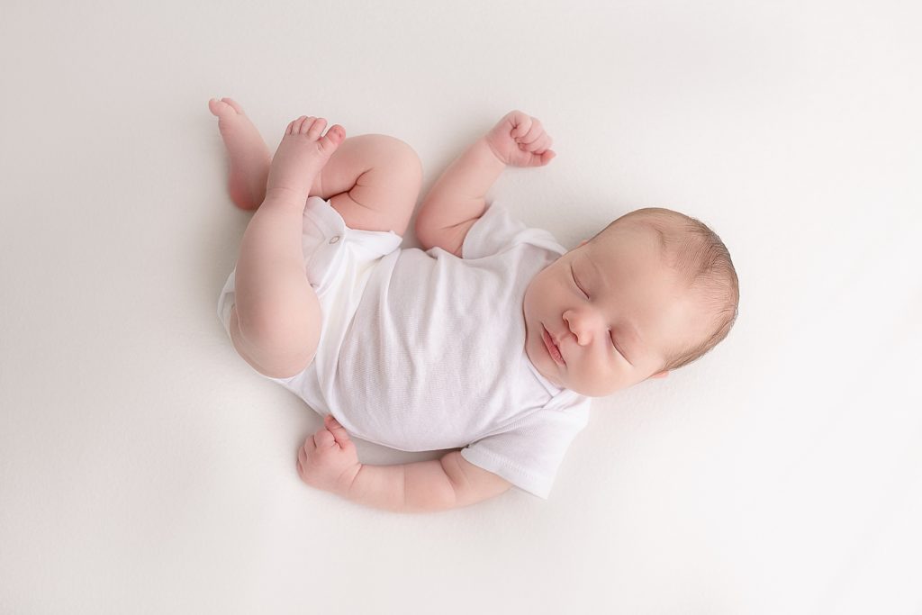 light-skinned newborn baby in white onesie sleeping on white blanket - newborn photos