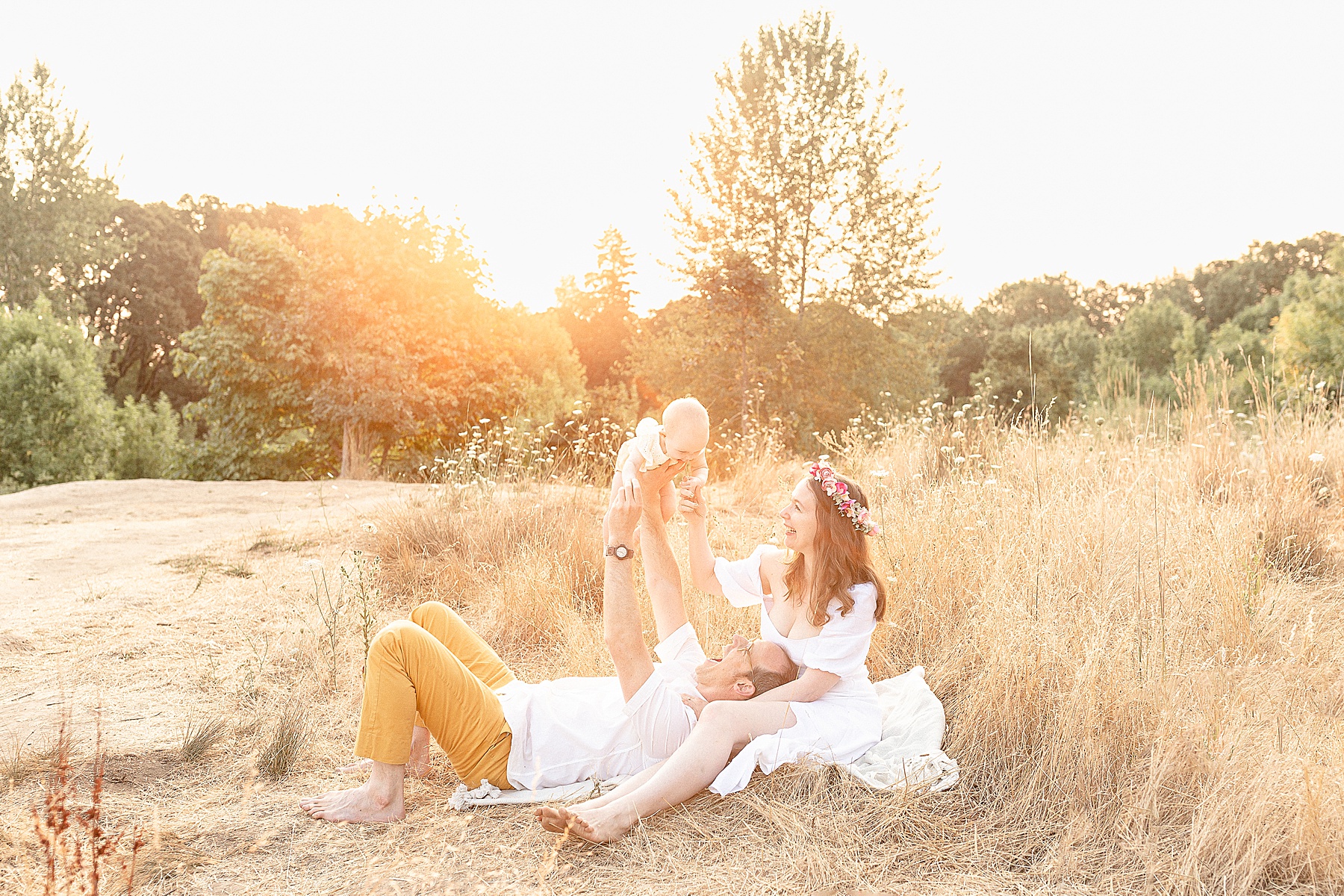 Light-skinned family of three in a field of tall golden grasses at a sunrise photo session in portland oregon