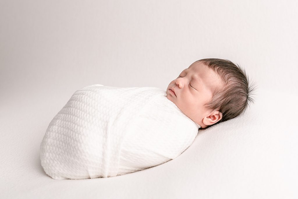 Sleeping newborn baby wrapped in white swaddle