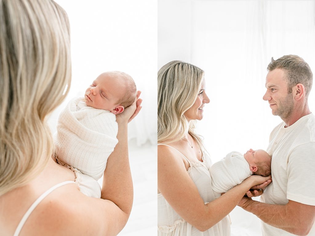 light-skinned mom and dad holding newborn wrapped in white - family in neutral tones