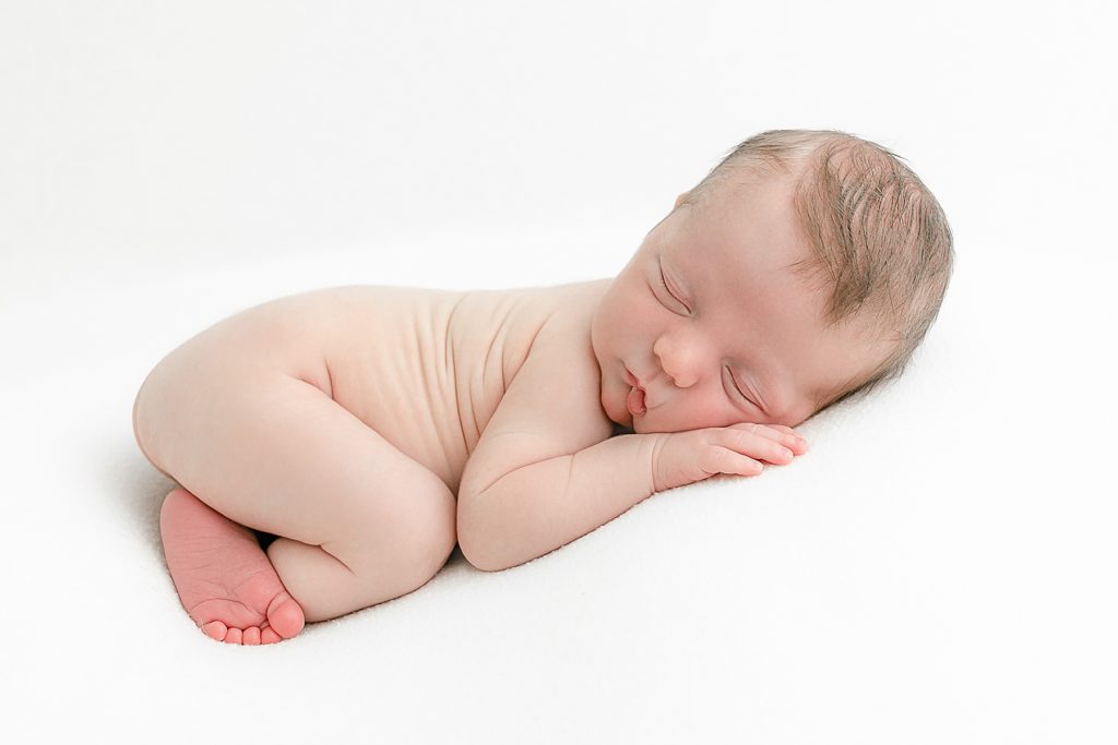 sleeping baby on white backdrop at newborn photography session