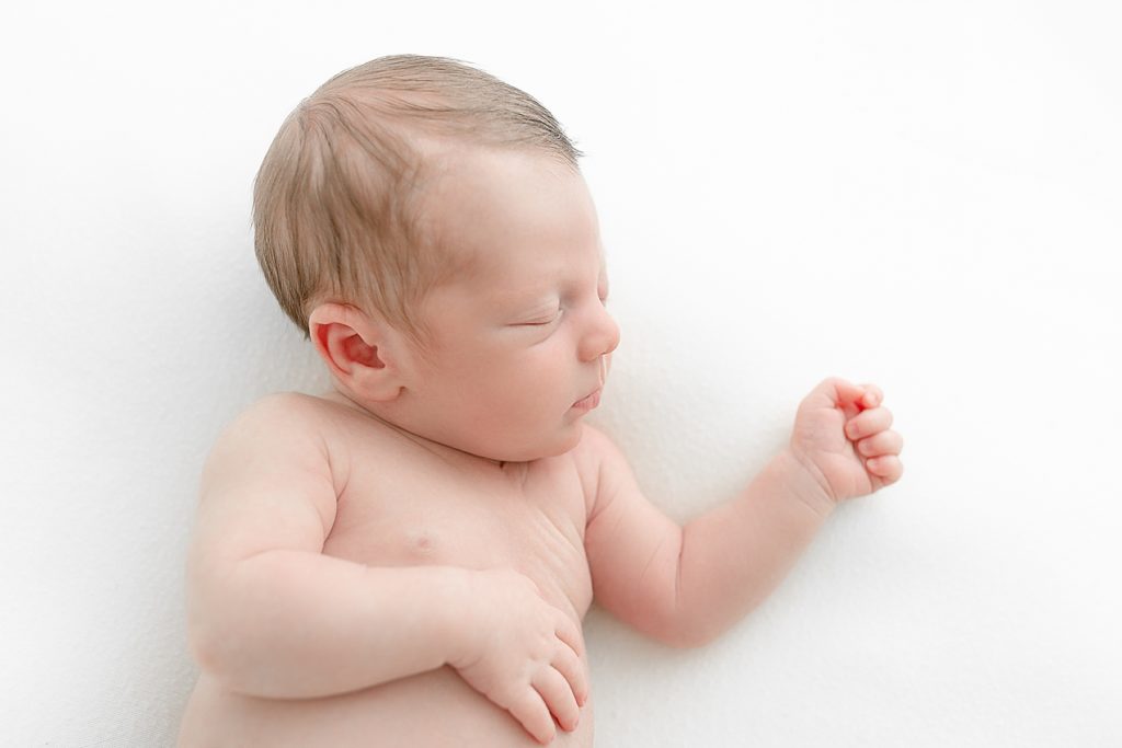 baby sleeping peacefully on white backdrop at minimalist newborn portrait session