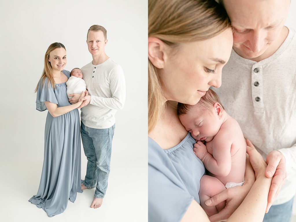 Mom dressed in blue and dad dressed in white top with light blue jeans on holding newborn baby at studio newborn session.