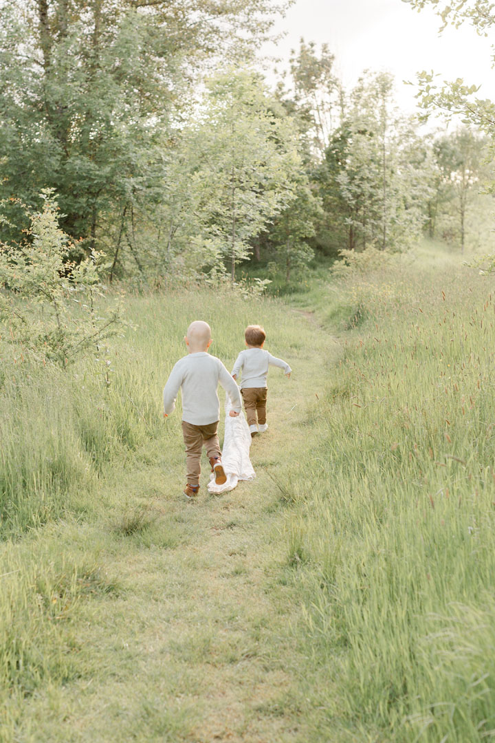 Two toddlers running away from the camera in a tall grassy field during their family photo session