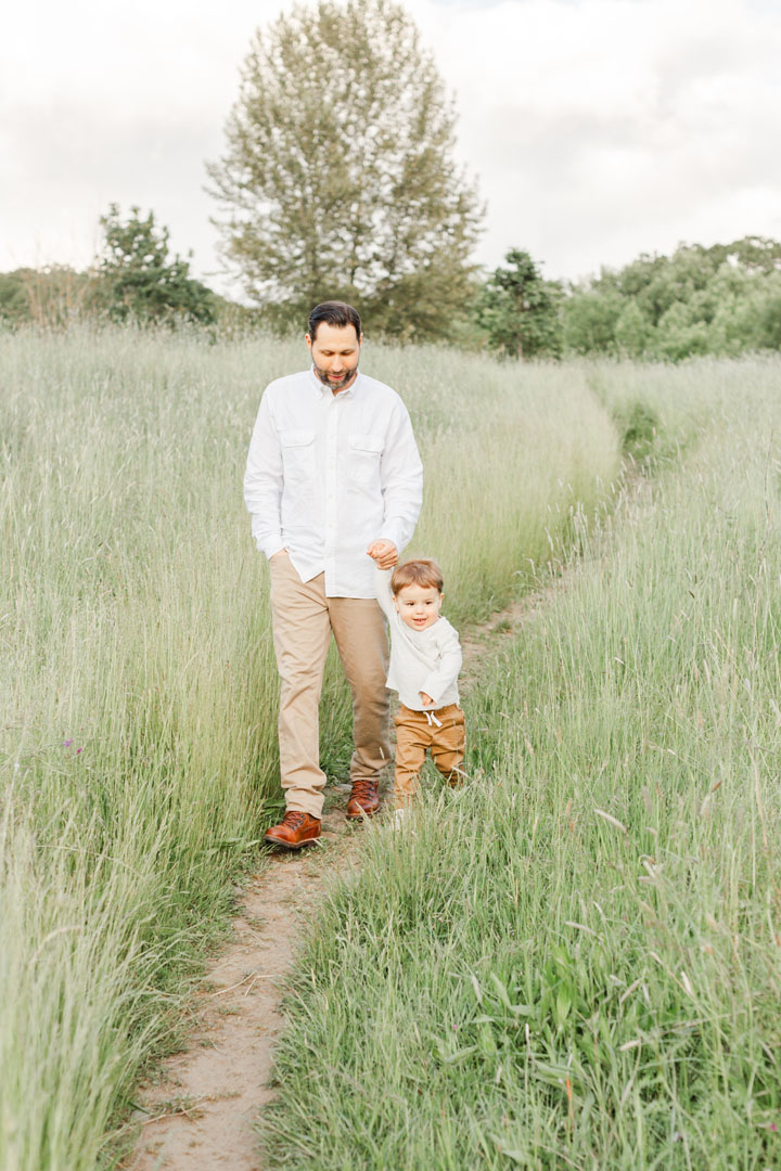 Dad and son walking through a tall grassy field at their portland photography session