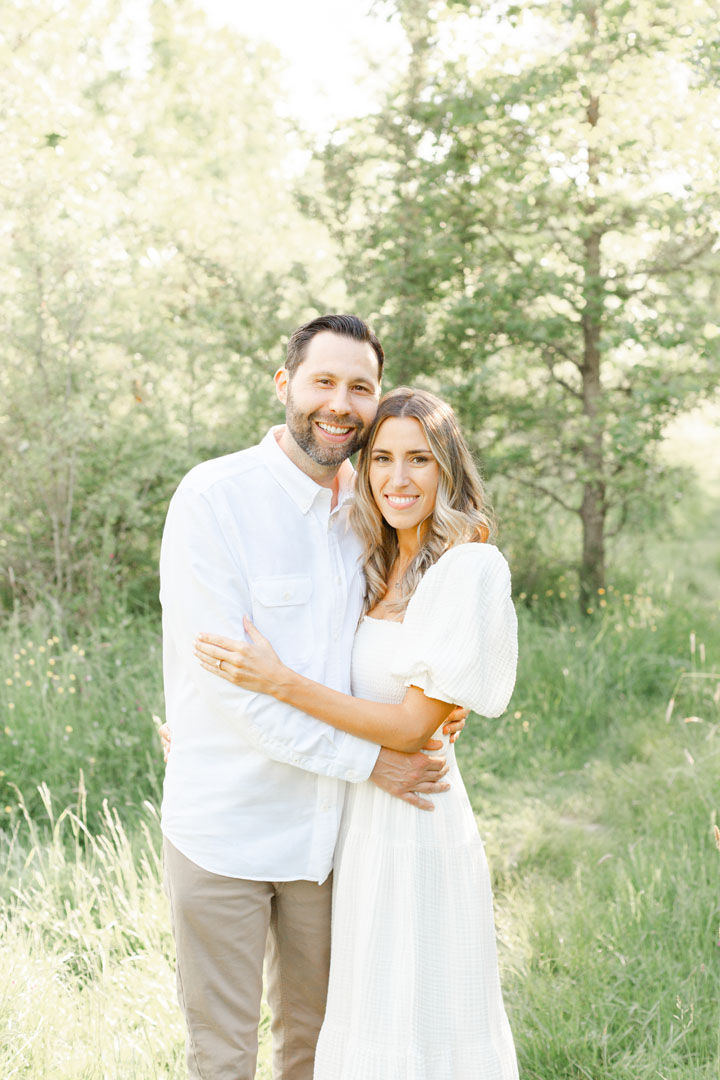 Mom and Dad standing close together and smiling at the camera during their family photo session with Ashlie Behm Photography