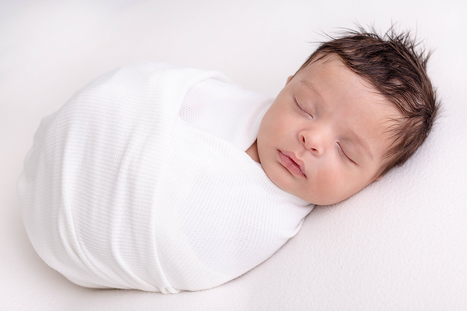 A newborn baby sleeps in a tight white swaddle Portland birth center