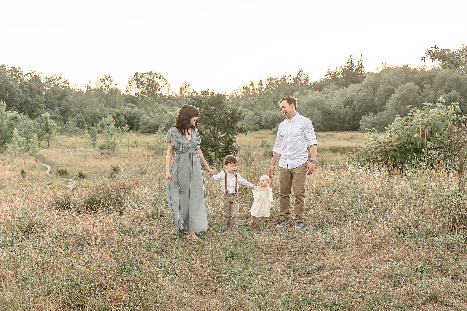 A family of four walk through a field of tall grass holding hands Portland Splash Pads