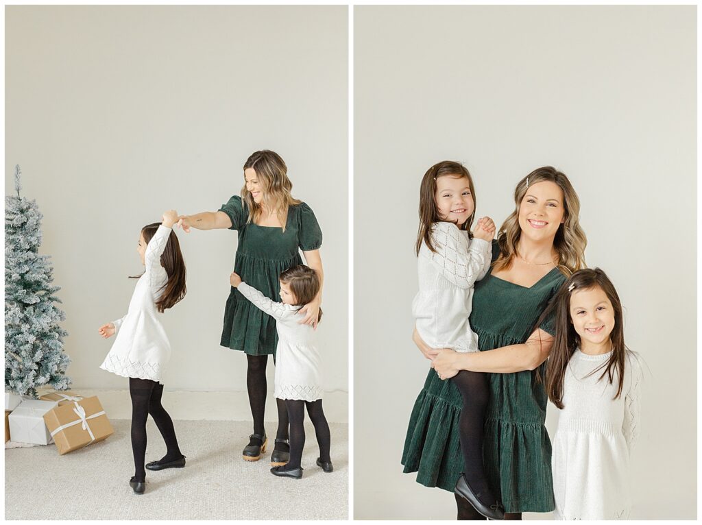 Mom in forest green dress is playing with her girls for their mini family studio session. Ashlie Behm Photography