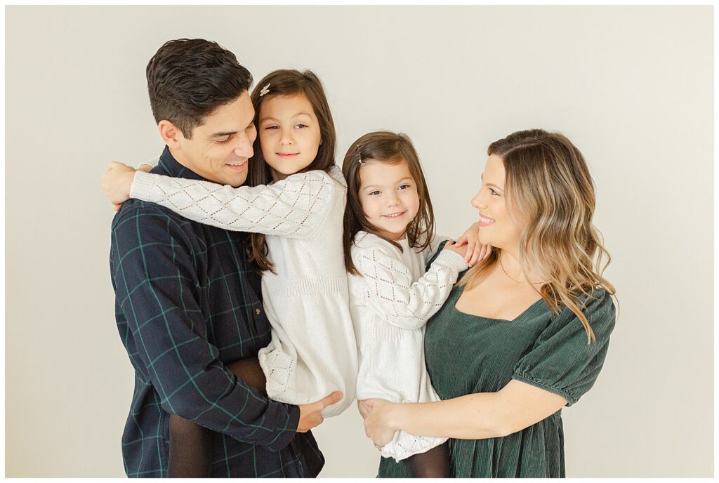 Family of four dressed in whites, greens and blues during their family studio mini portrait session at a studio in NW Portland, Oregon. 