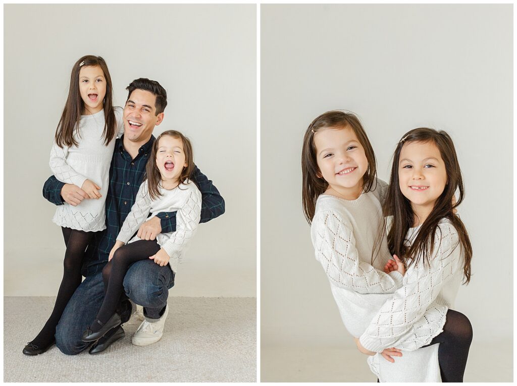 Dad in blues and greens and two daughters in white dresses with black tights being cute together during their studio mini sessions with Ashlie Behm Photography