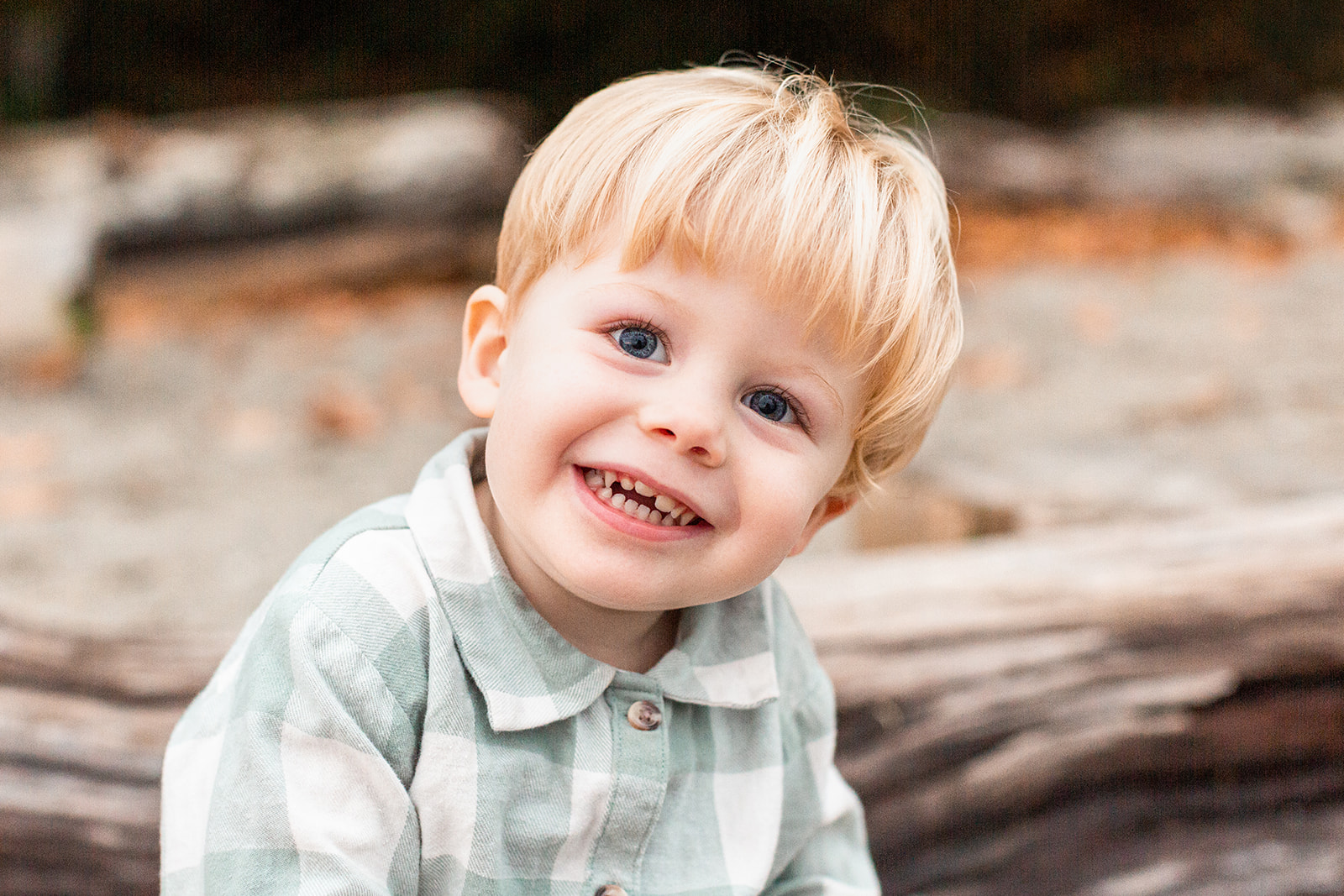 A young toddler boy smiles big while sitting in a green plaid shirt after visiting Portland Baby Shower Venues
