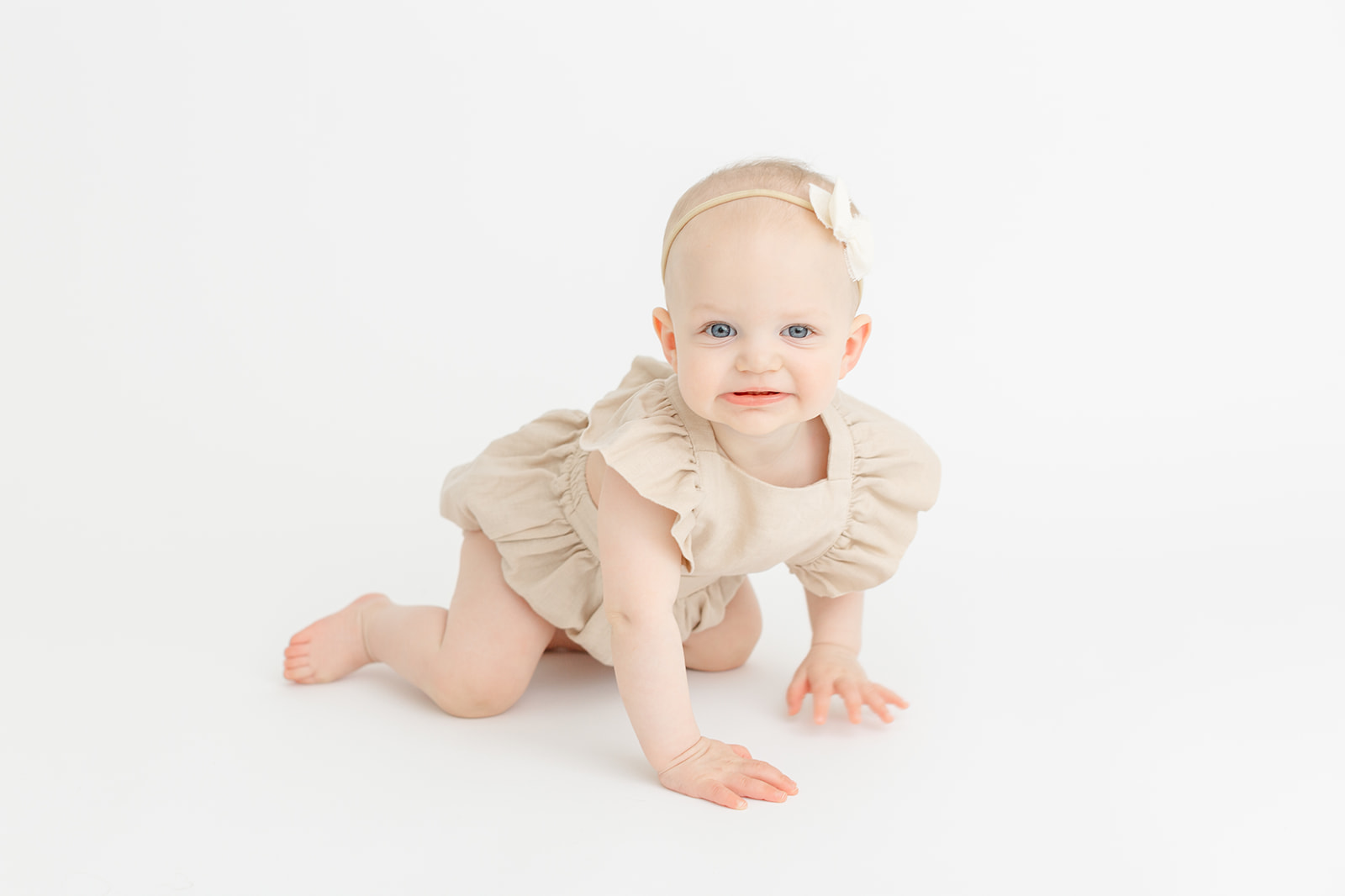 A toddler girl in a beige dress crawls of the floor of a studio after visiting The Wiggle Room Portland