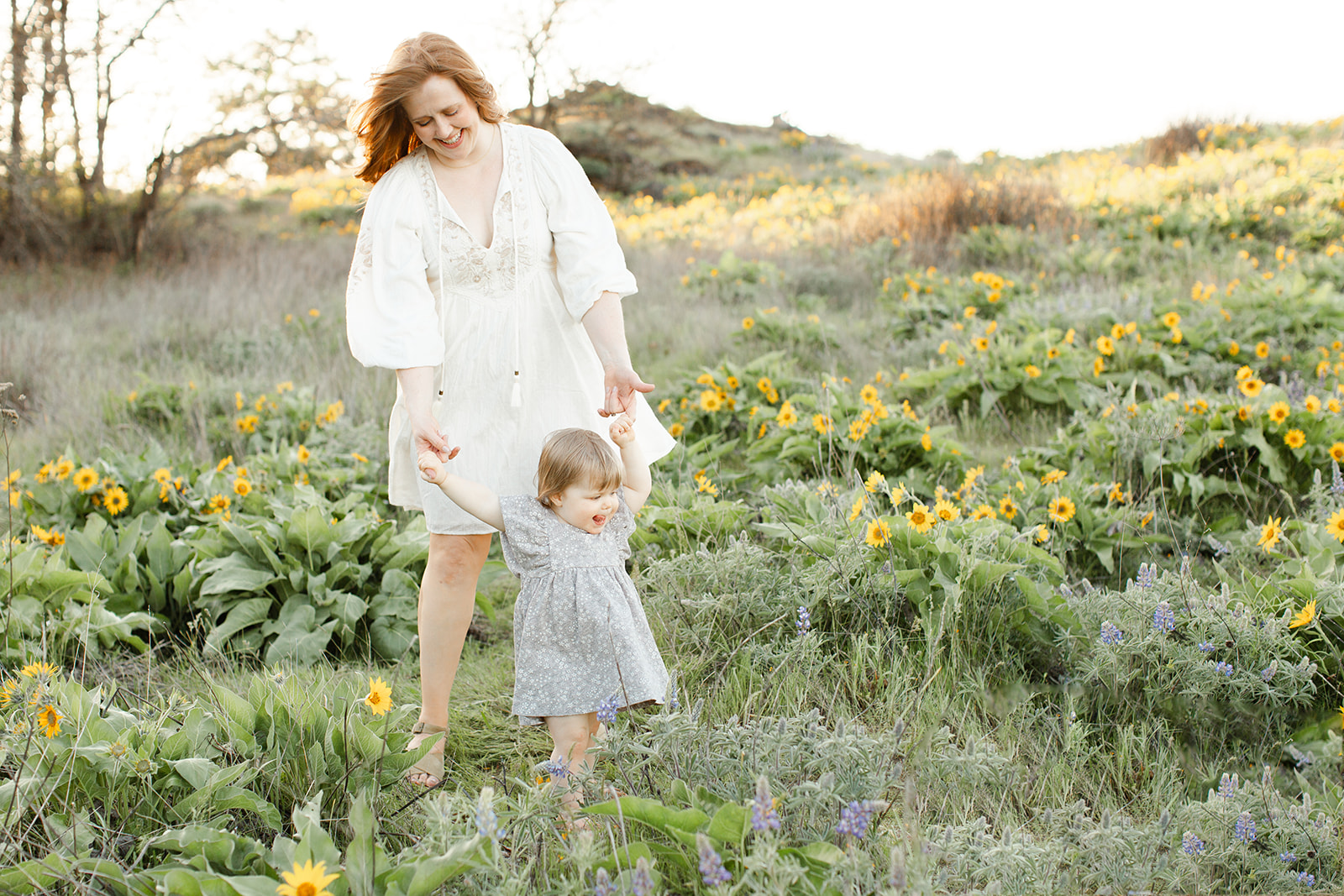 A happy mom explores wildflowers with her toddler daughter at sunset during toddler activities Portland