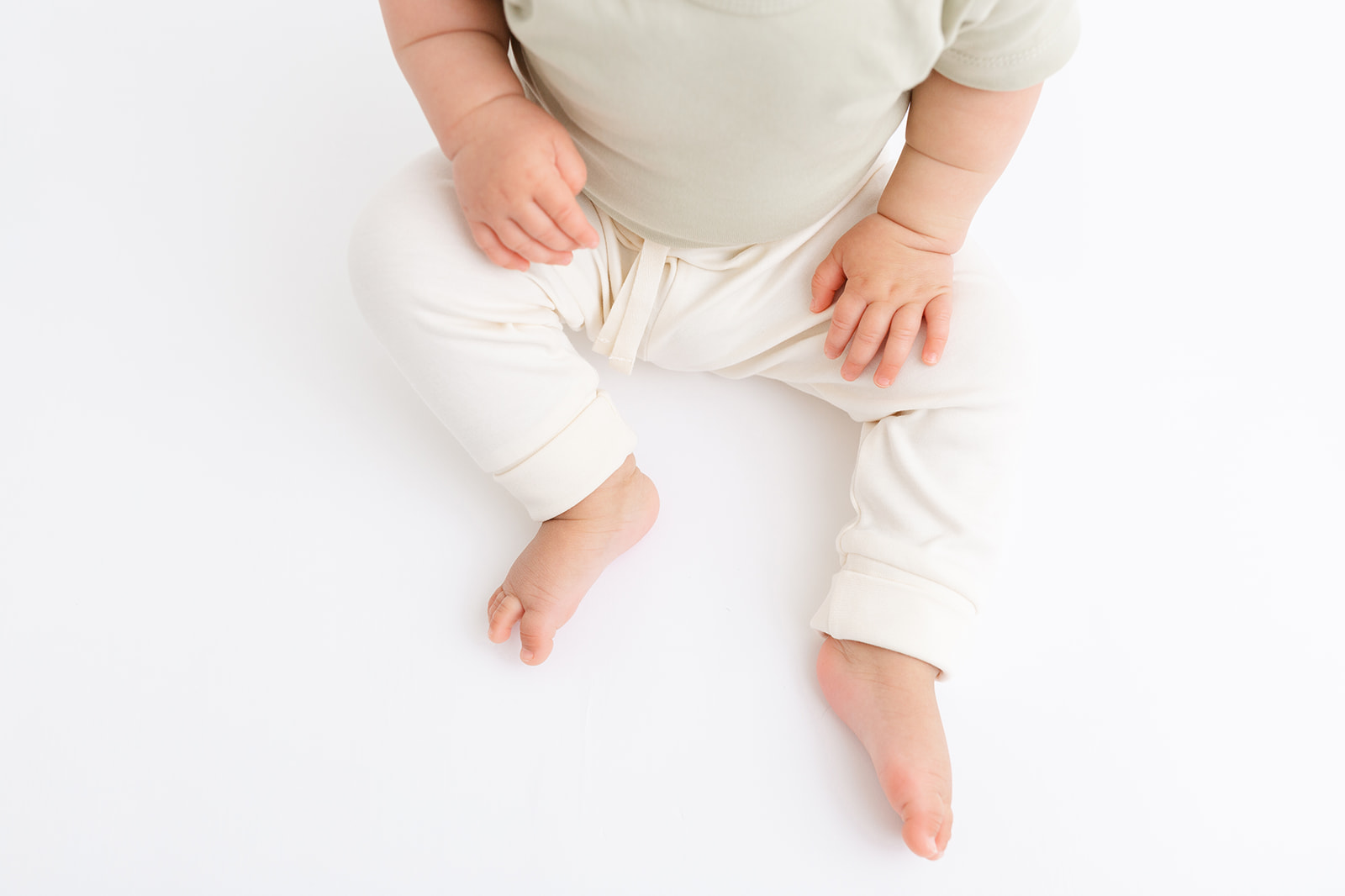 Details of a sitting toddler's legs and hands before some Swim Lessons Portland