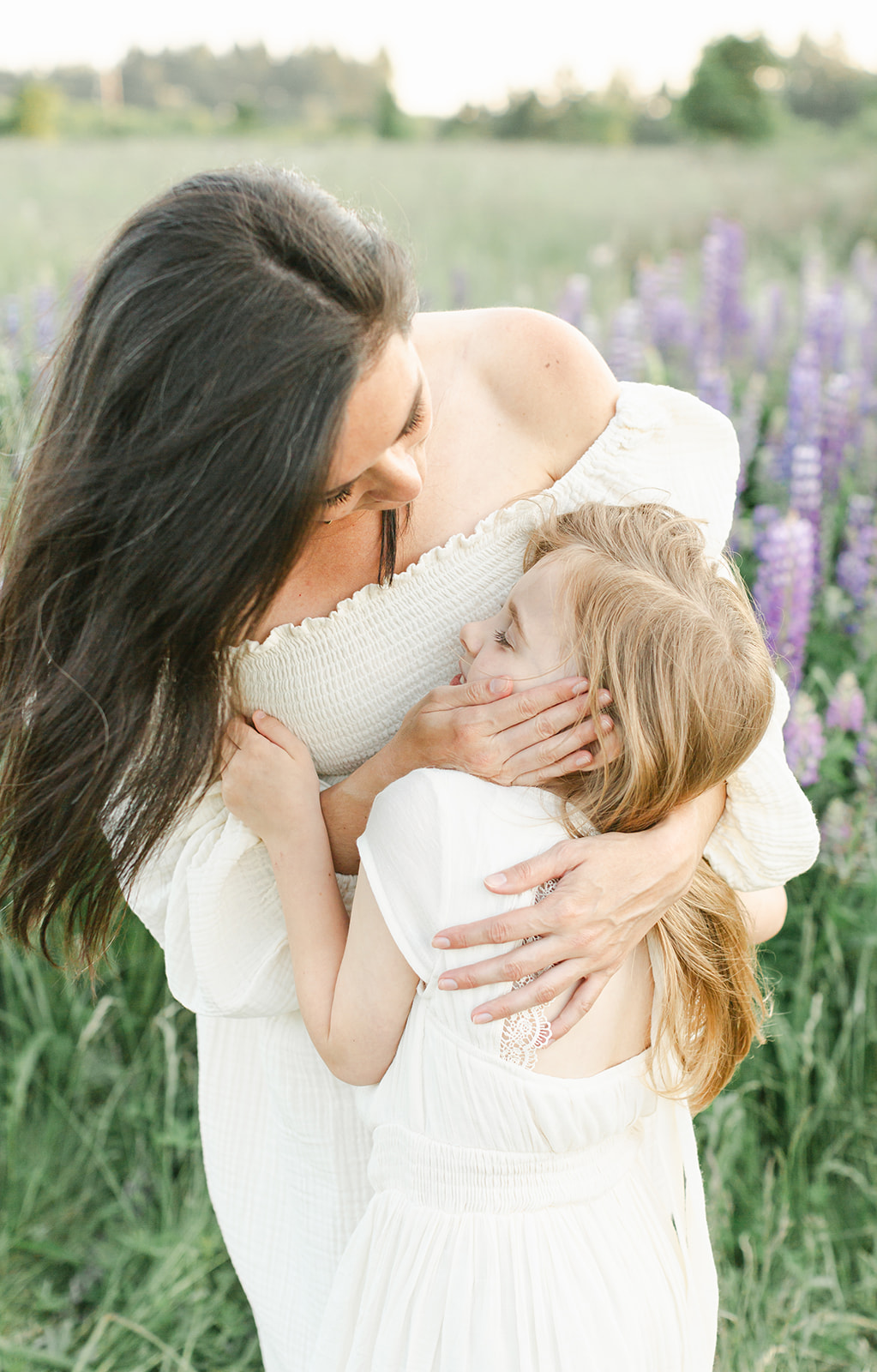 A mother and young daughter hug and snuggle in a lavender field after some Mamaspace Yoga