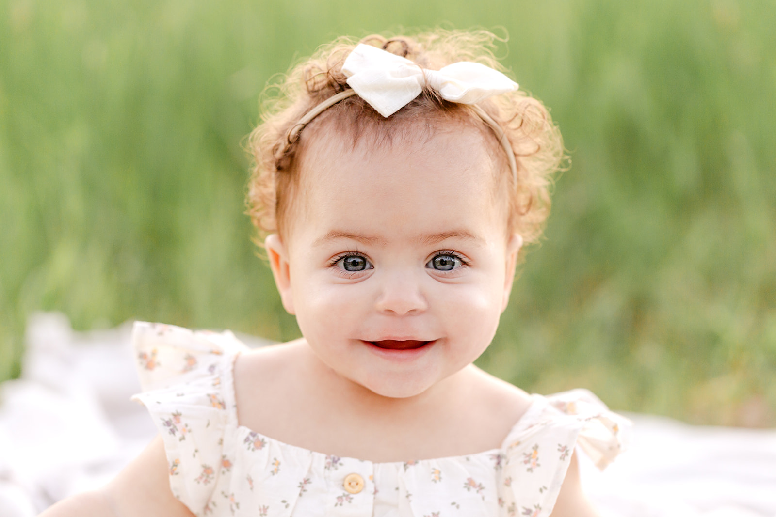 A close up of a toddler girl in a dress in a park