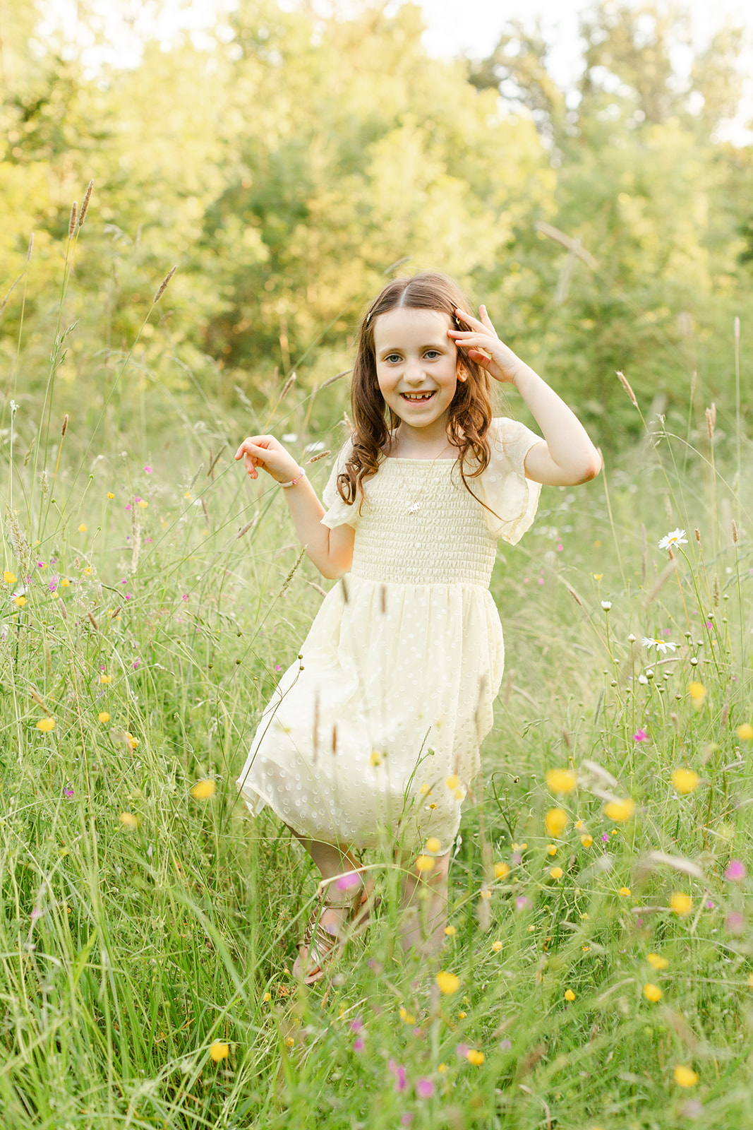 A young girl in a yellow dress walks through a field of colorful wildflowers at sunset