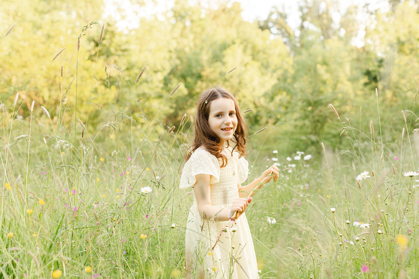 A young girl in a yellow dress explores a field of wildflowers at sunset after meeting NorthWest Nannies