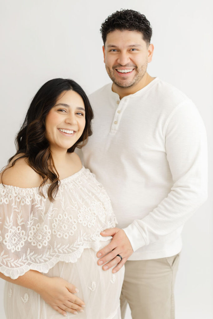 Partner gently resting a hand on an expecting mother's belly during maternity photos